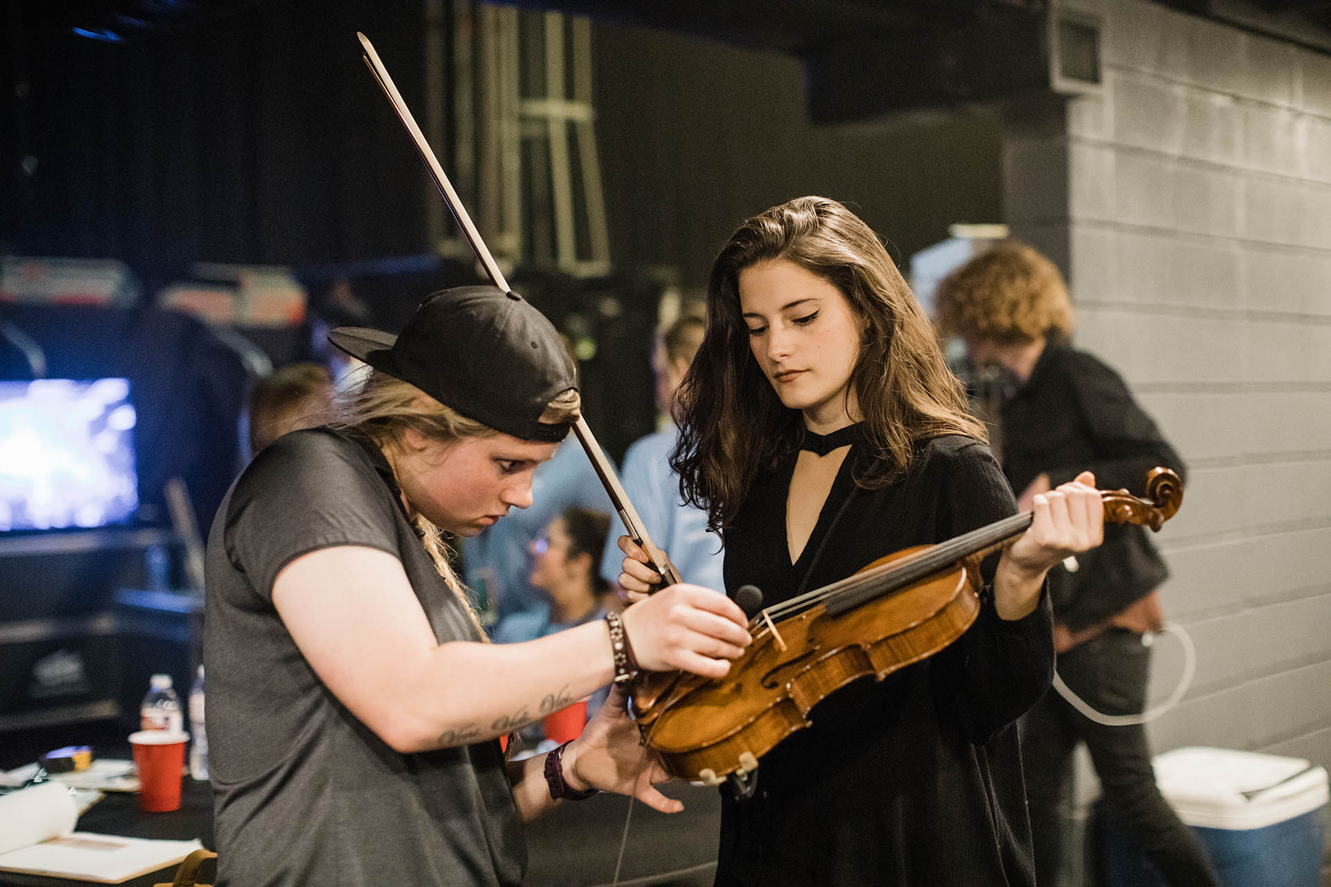 Concert photos Dallas Photographer; candid photo of a roadie and violinist preparing a violin for a performance backstage.