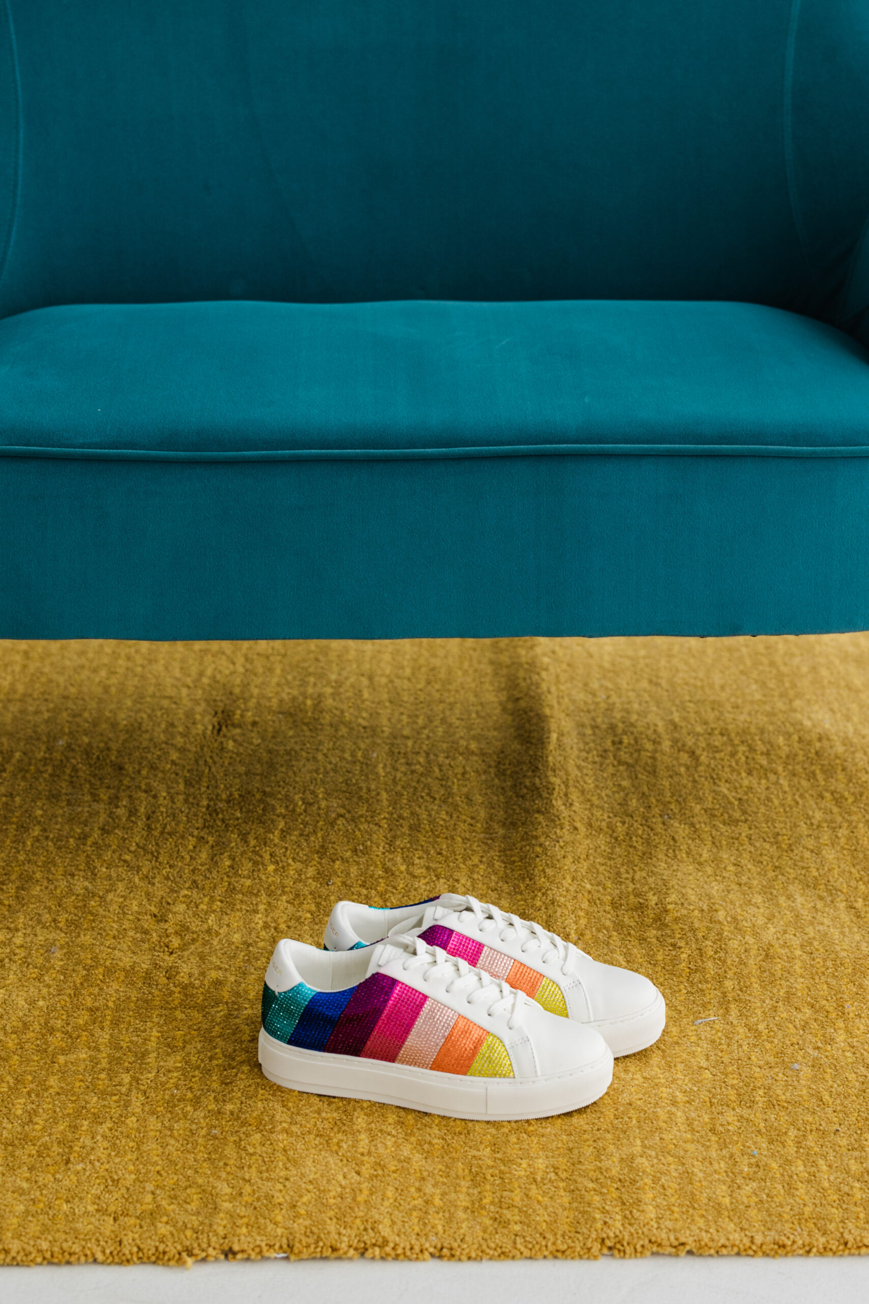 a pair of sneakers with rainbow colors on a tan carpet