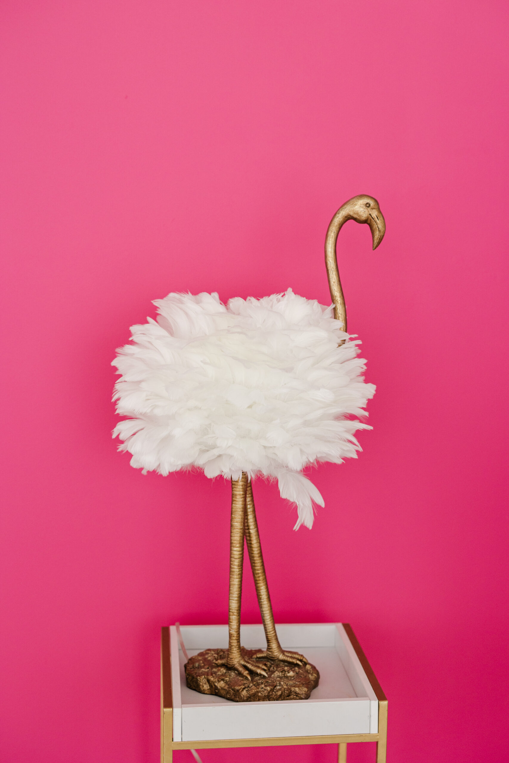 a flamingo statue with white feathers set against a pink backdrop
