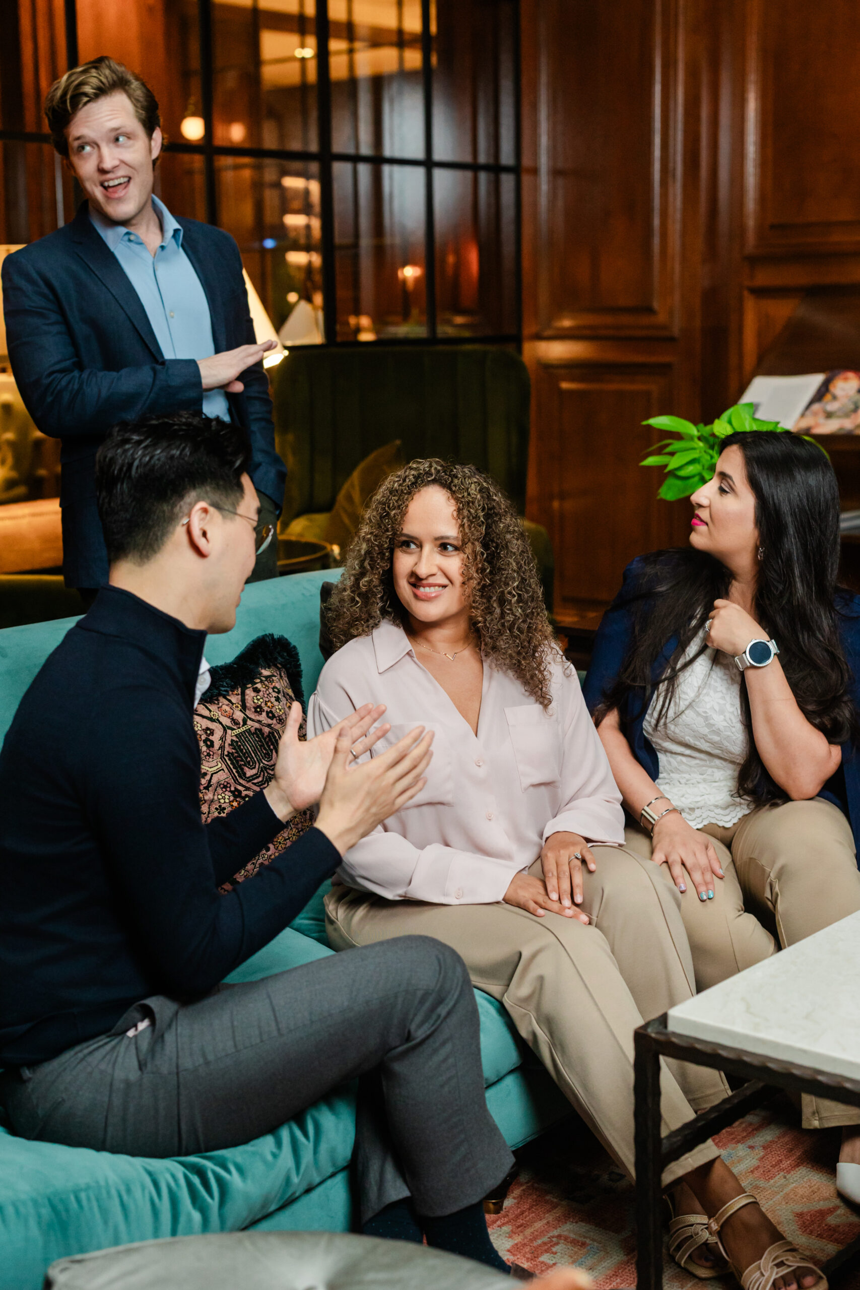 a group of co workers sitting together on a blue couch and conversing 