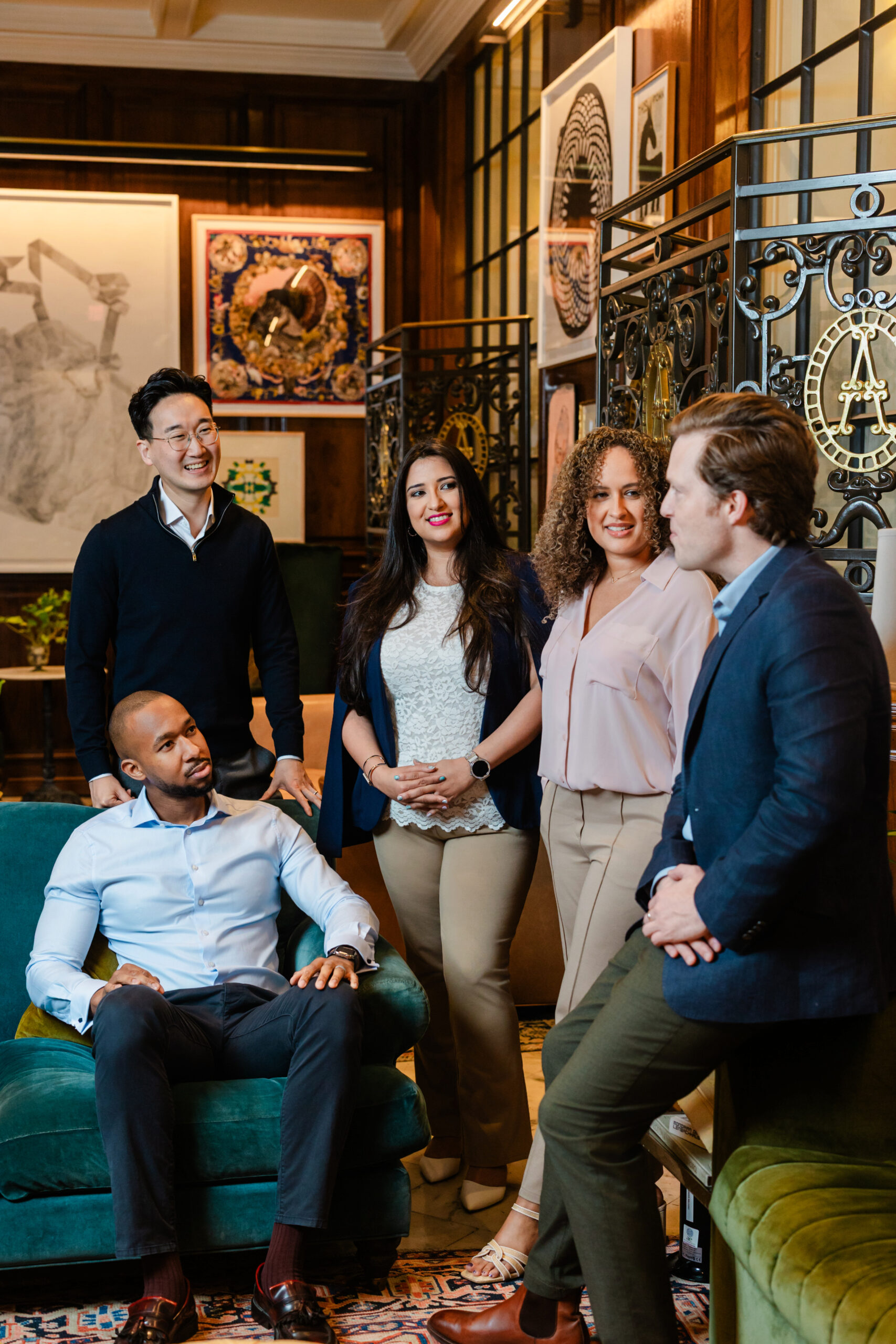 a group of coworkers standing together in the adolphus hotel and conversing with each other 