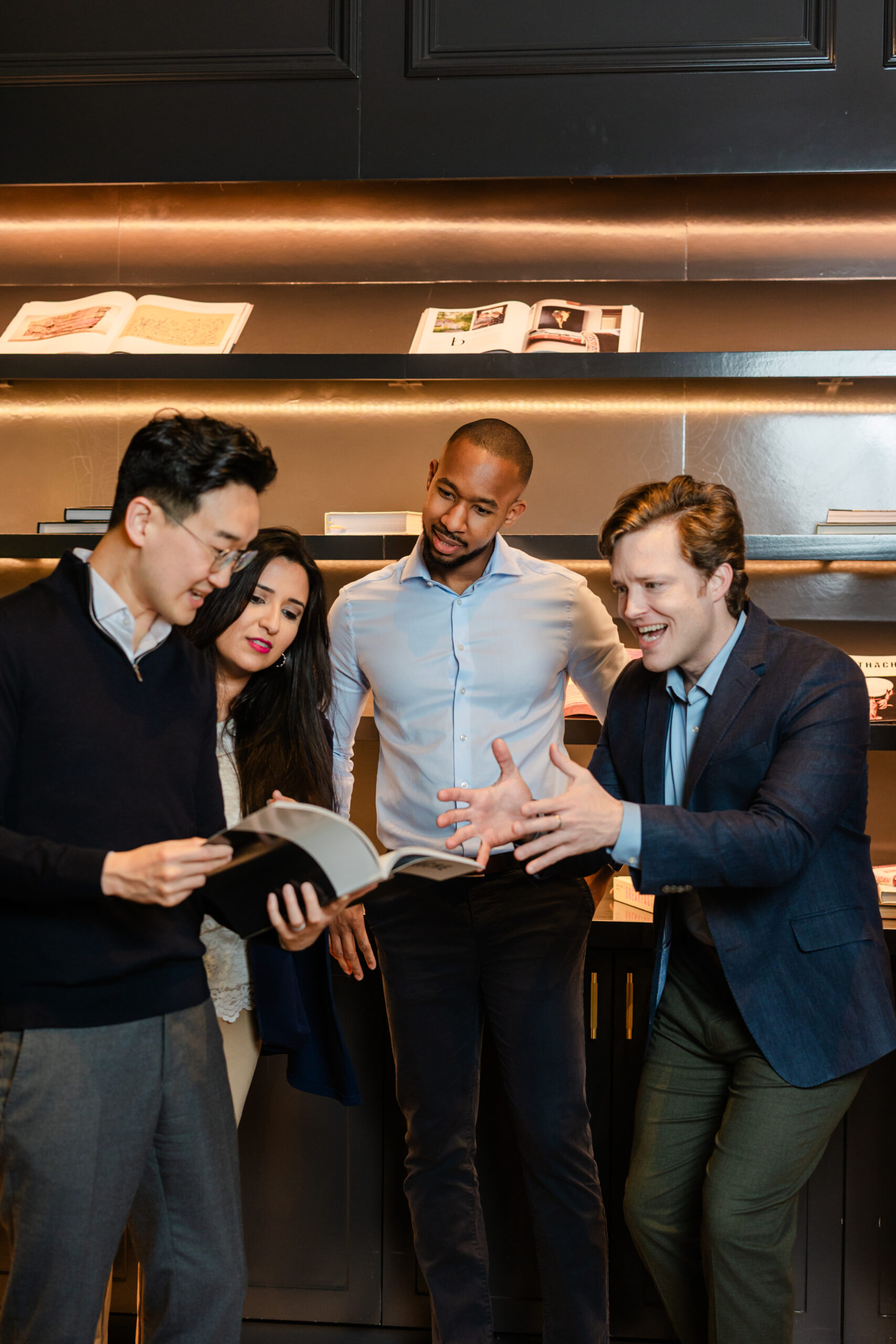 a group of coworkers looking through a magazine together and talking 