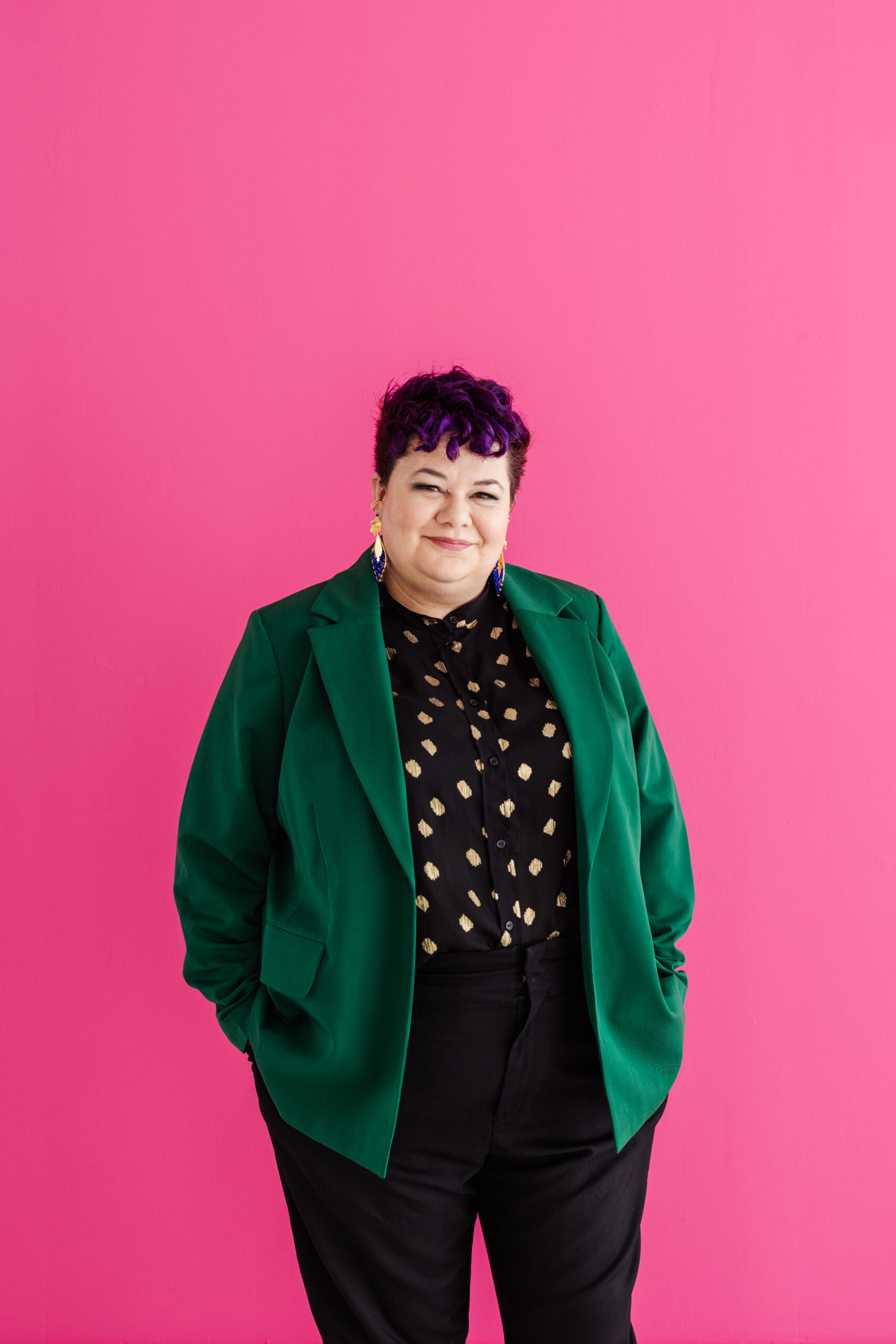 a woman taking a colorful headshot in front of a bright pink backdrop 