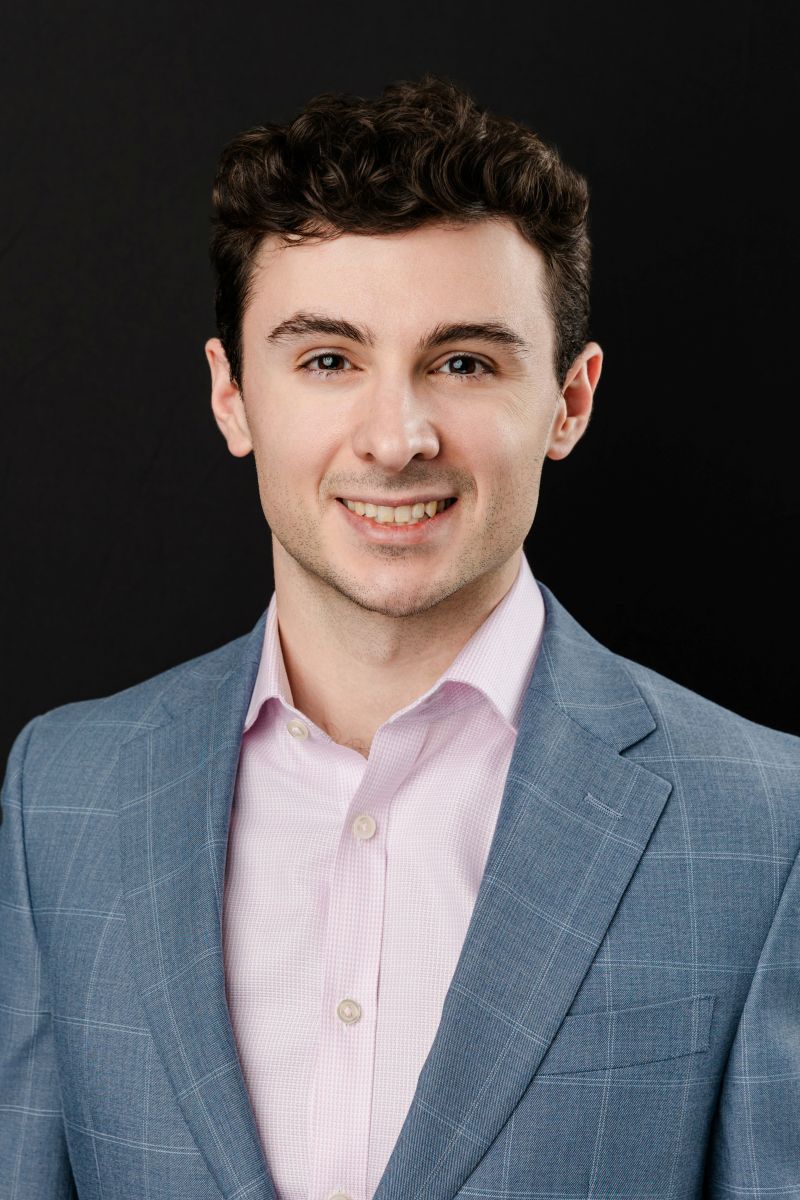 a man wearing a suit jacket taking corporate headshots in dallas against a black backdop 