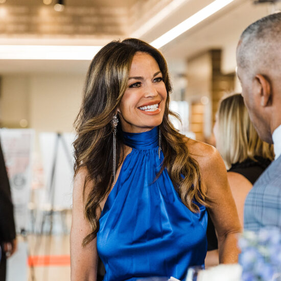Dallas Corporate Event Photographer. Photo is of a smiling Caucasian woman in a blue dress at a corporate event.