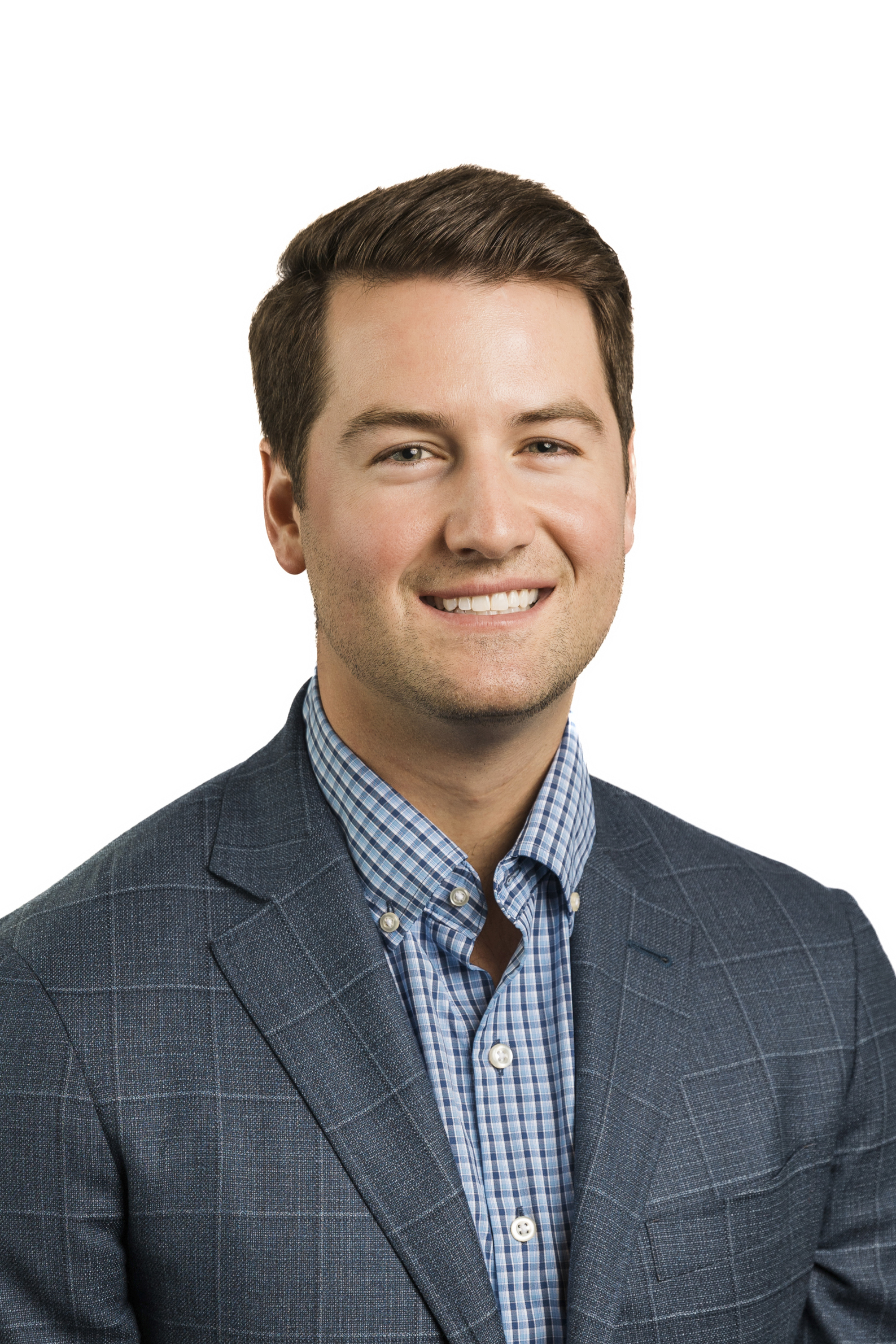 Dallas Corporate Head Shot Photographer: a head shot of a corporate male employee in front of a white background. He's wearing a blue dress shirt and a plaid jacket.