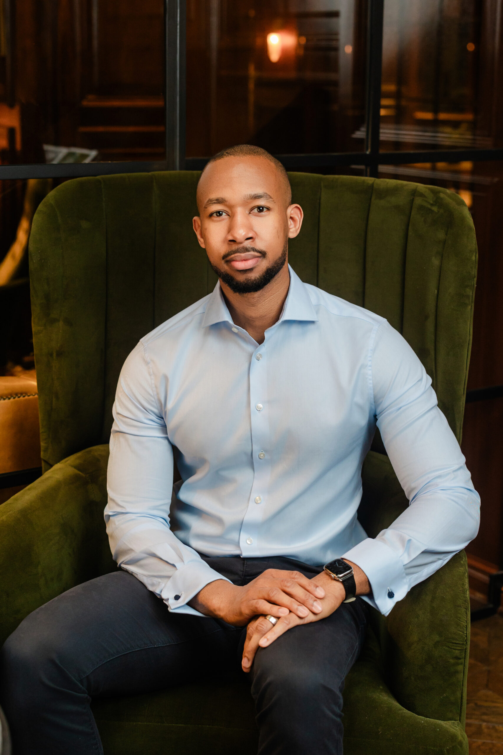 a man taking a formal corporate headshot sitting on a green chair 