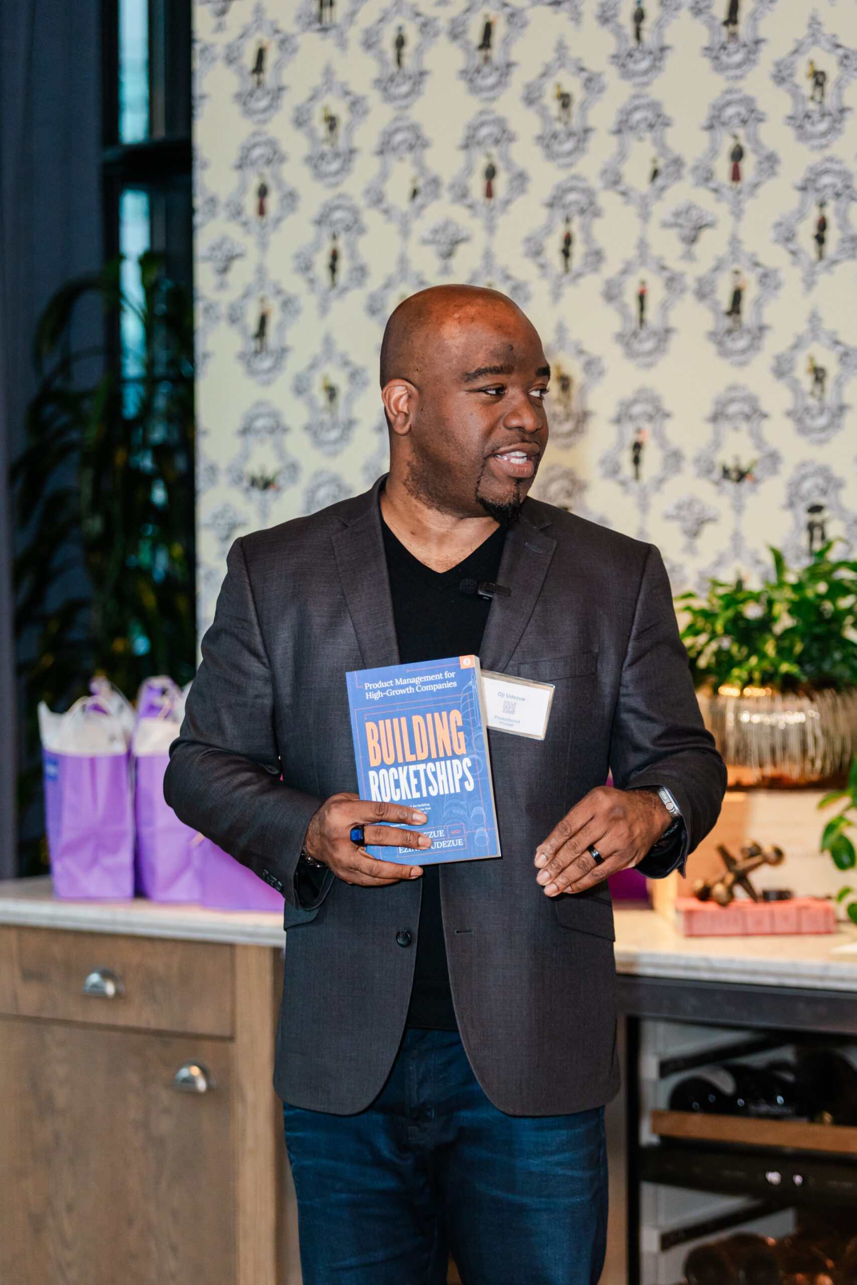 a man holding a book and giving a speech at a corporate networking event