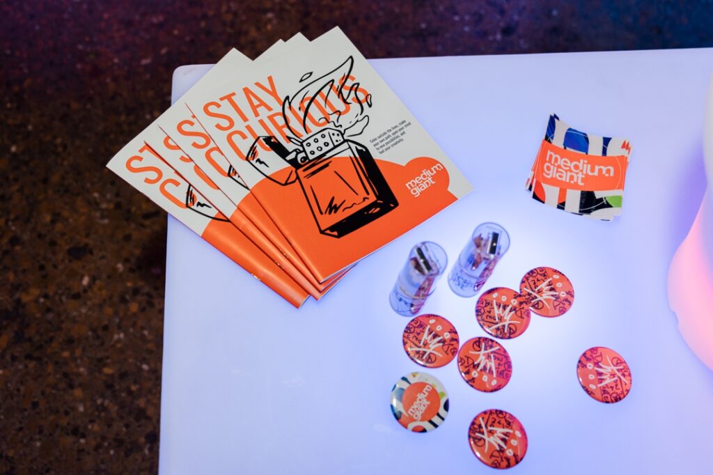 Event guides, buttons, pencils, and stickers from the media company, medium giant, sitting on a white table