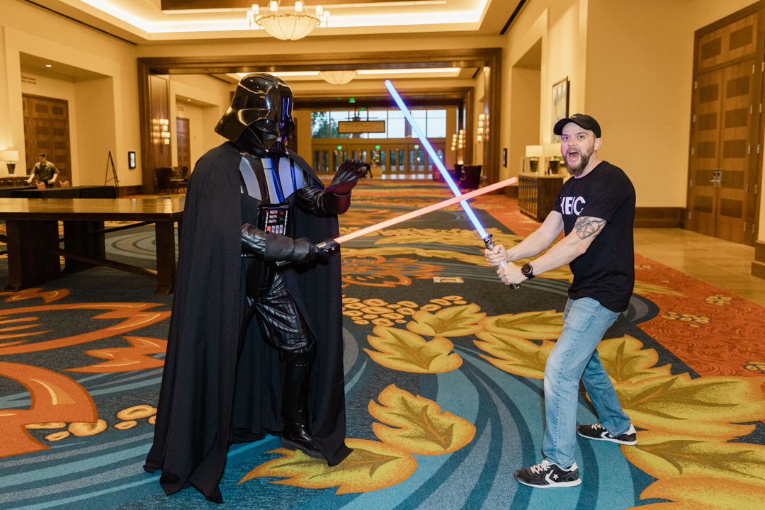Dallas Fort Worth Team Building Event Photographer; photo of Darth Vader and an employee preparing to duel with lightsabers at a team building event.