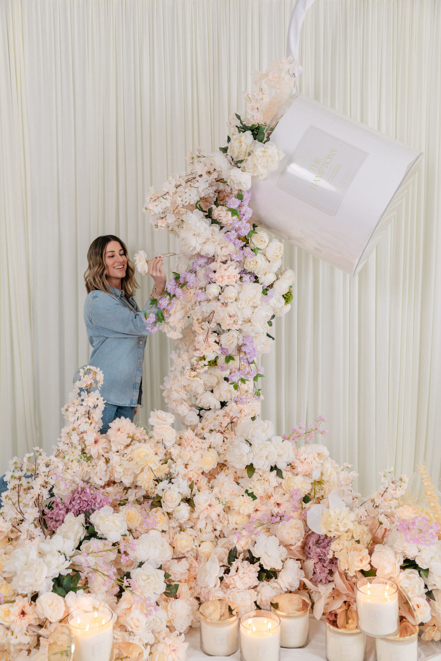 the founder of Life In Lilac smelling flowers and standing next to her company's candles 