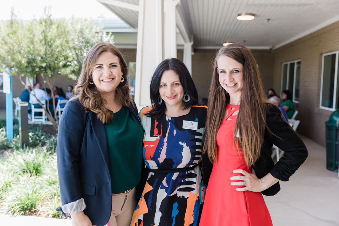 Dallas Nonprofit Event; photo of three women in business attire standing close together, smiling, and posing for a photo at an outdoor event.