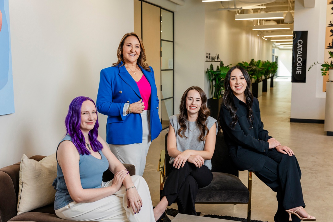 Four smiling standing and sitting while posing together in an office