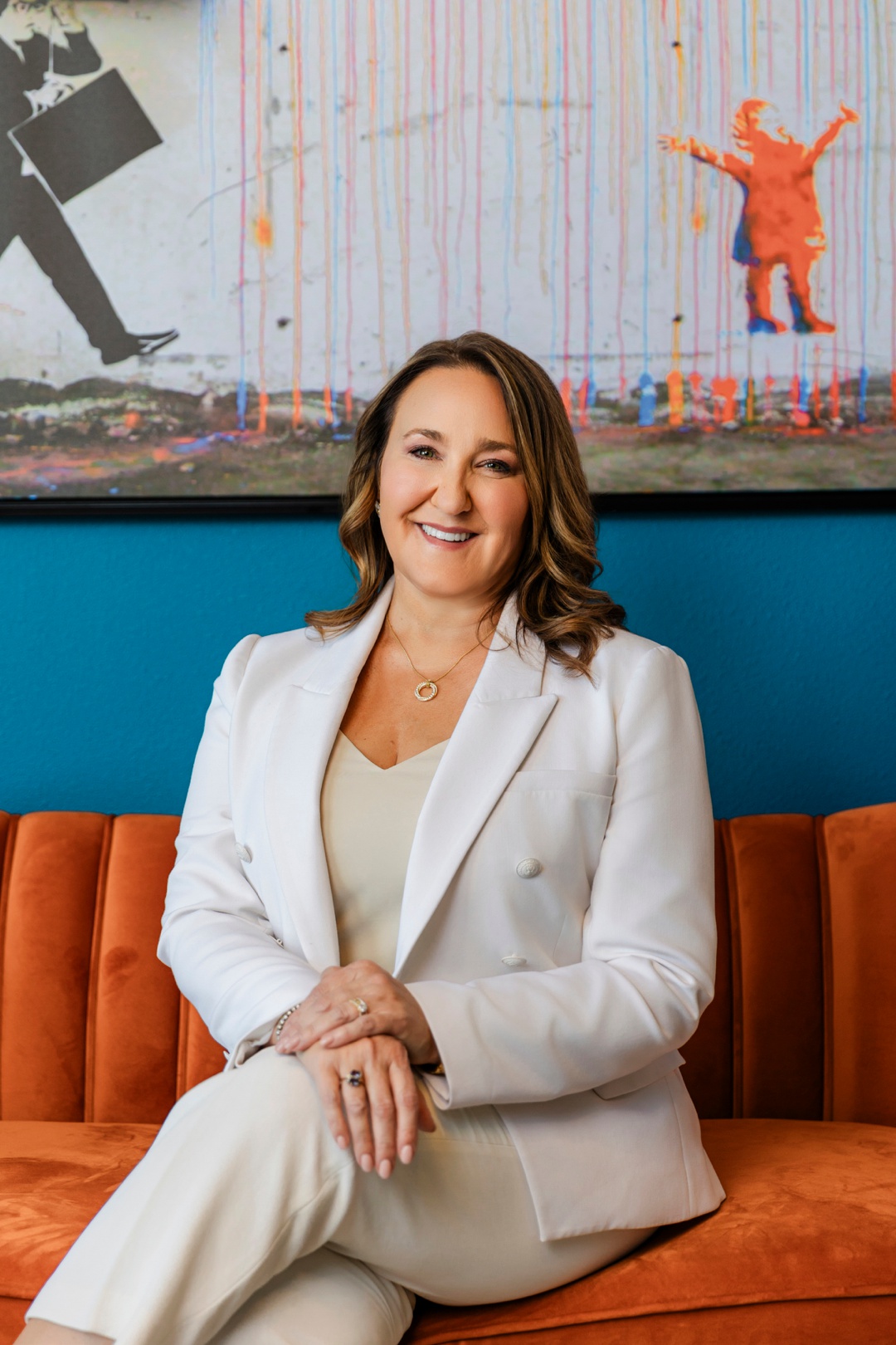 A smiling woman sitting with crossed legs on an orange couch