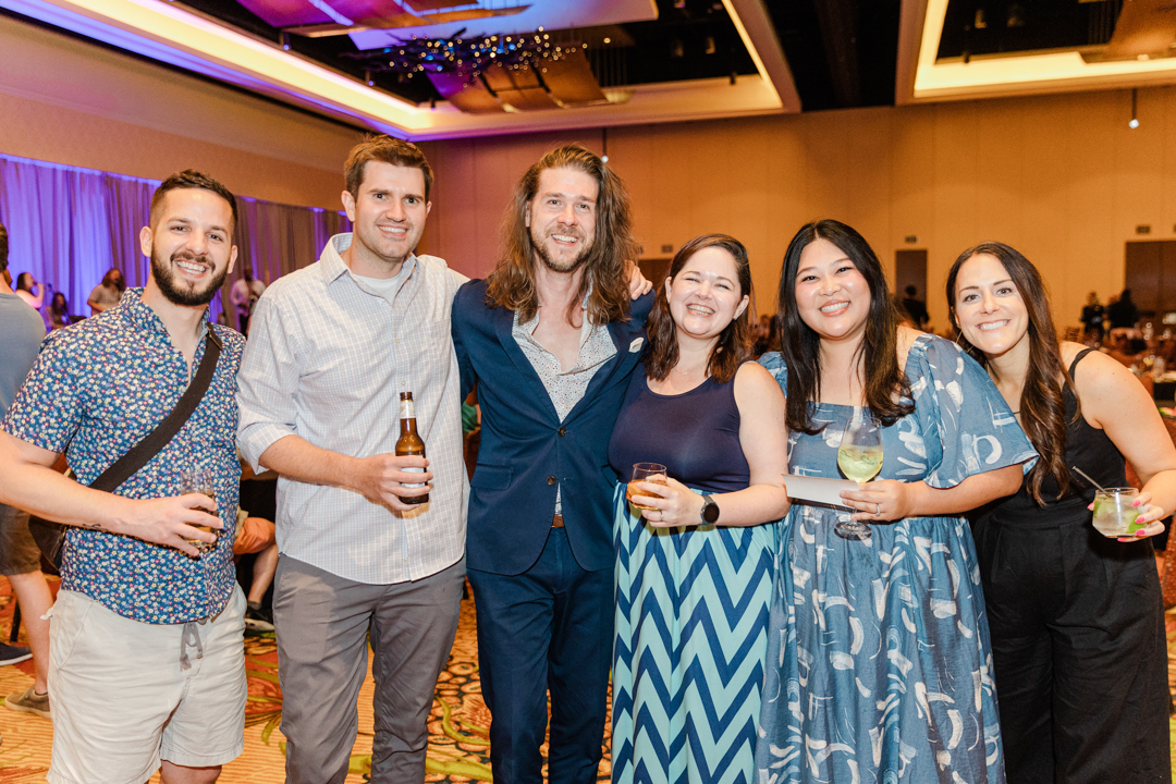 DFW corporate event photographer; corporate event photo of three men and three woman in business casual dress all smiling and posing for a photo while holding their drinks.