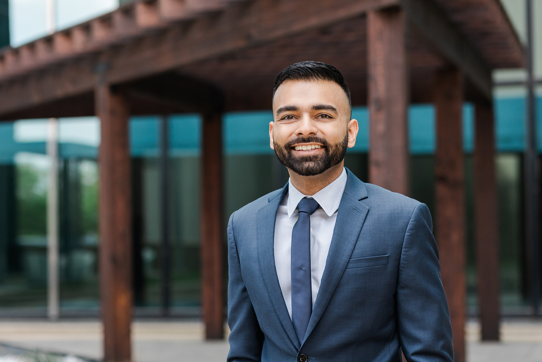 DFW Corporate Head Shot Photographer: a head shot of a man outside of his office building. He's wearing a navy suit and tie.