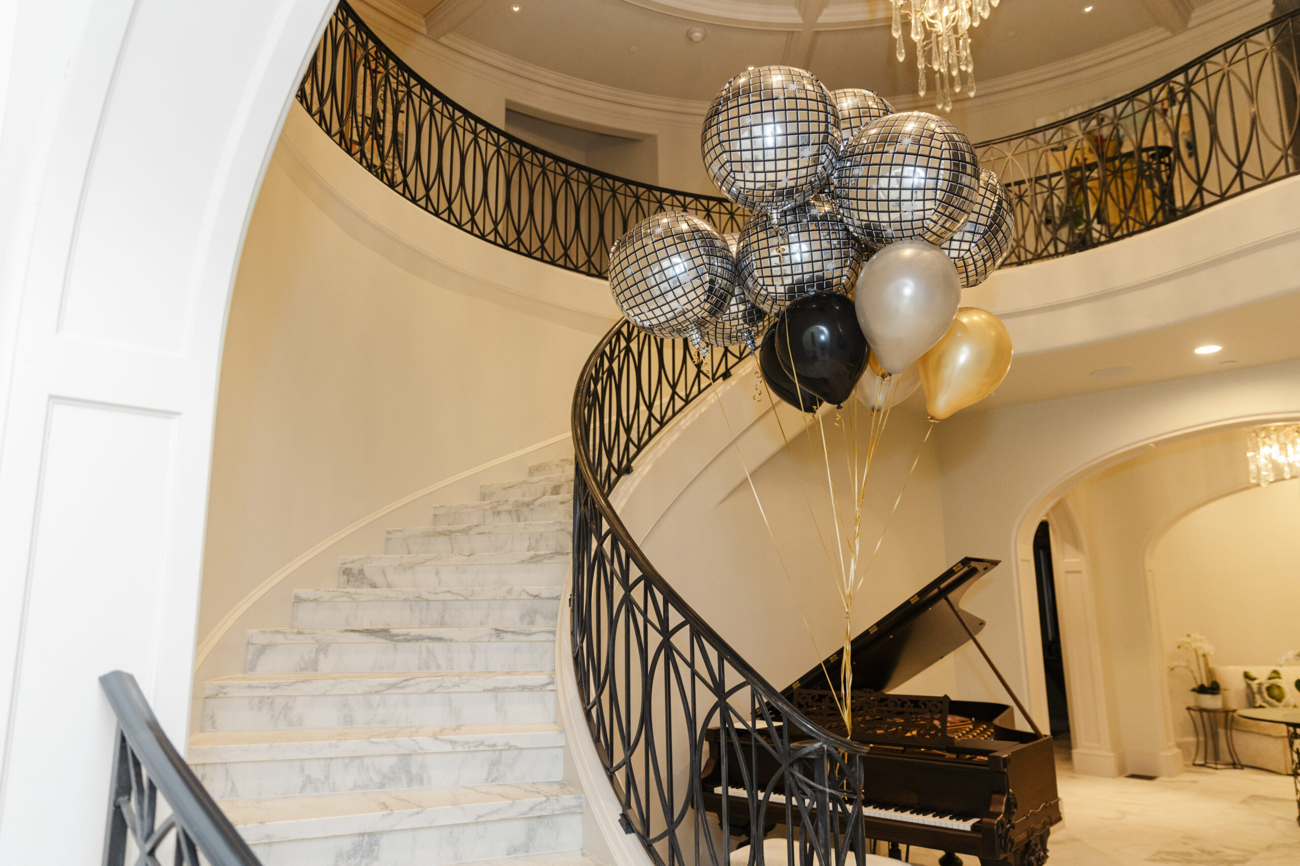 a group of balloons tied to a staircase next to a pian