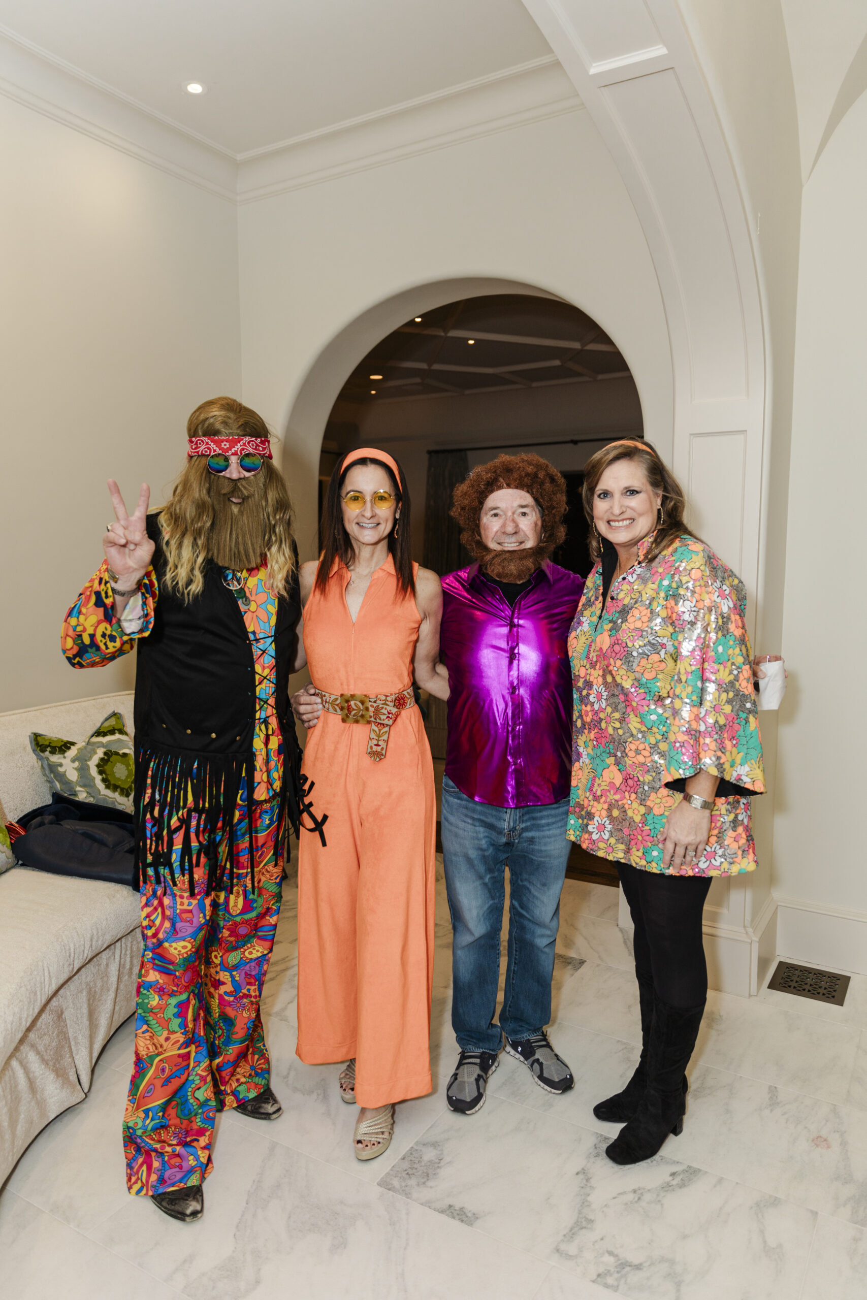 a group taking a photo in a living room in 60's themed attire
