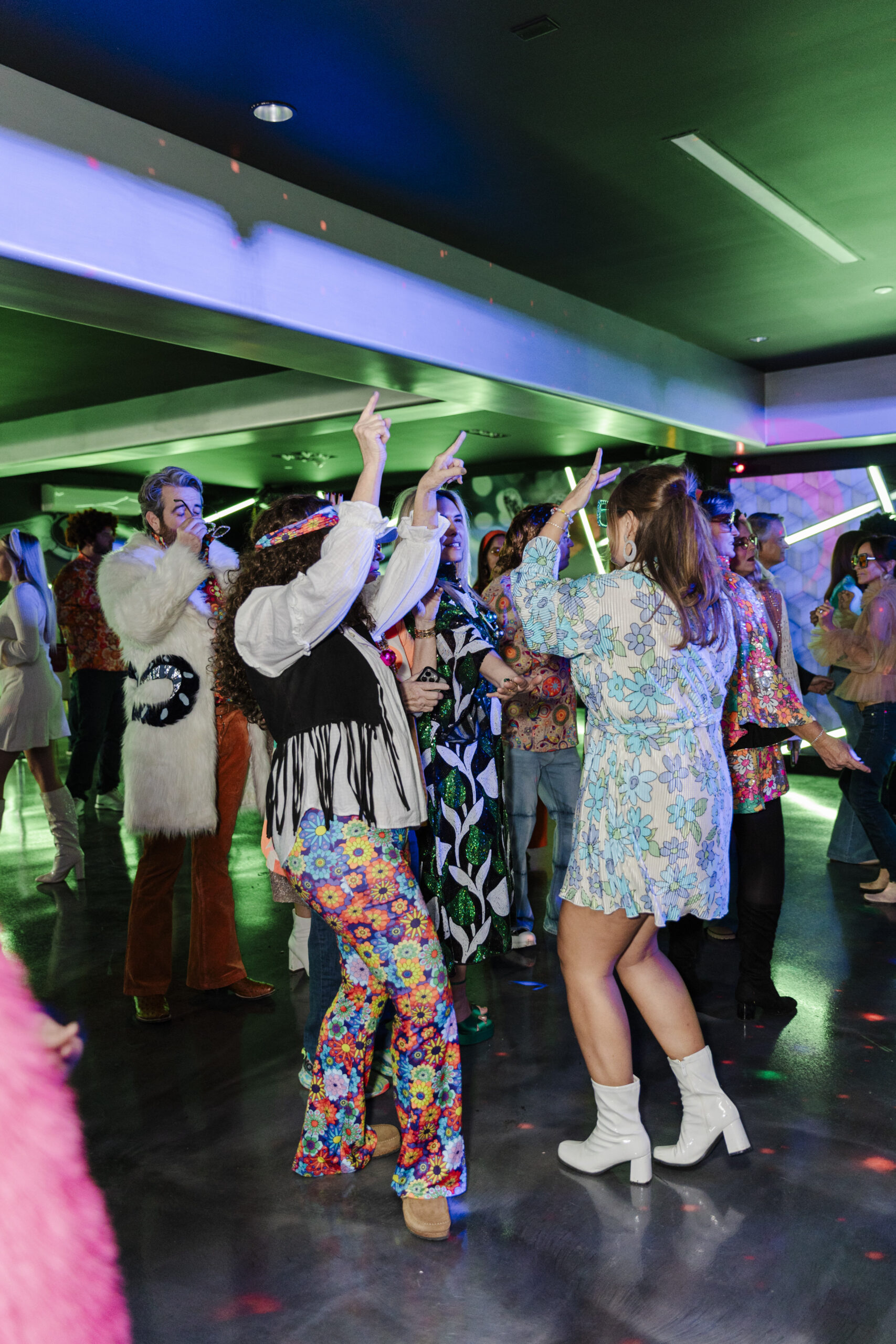 a group dancing in a room at a 60's themed birthday party