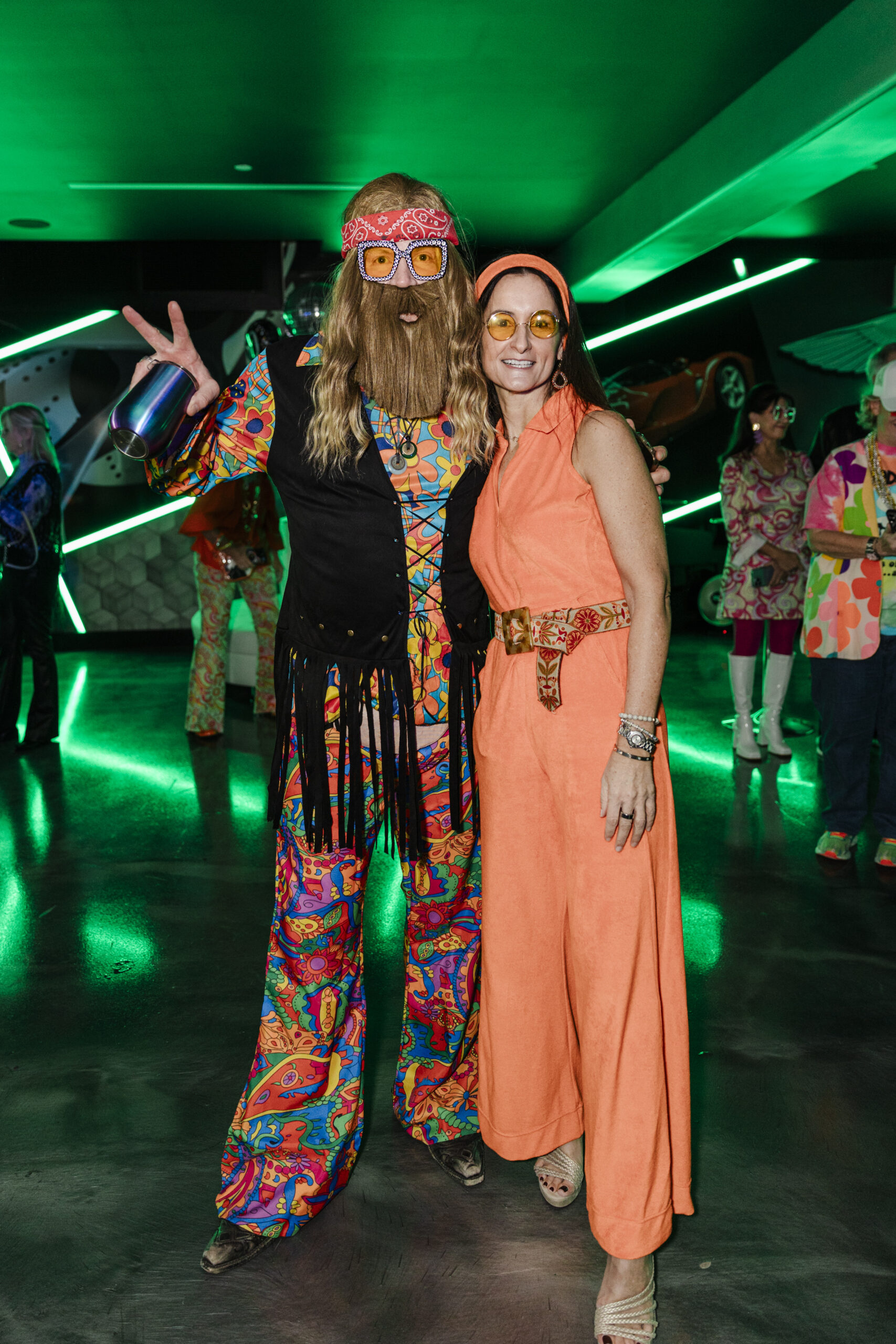 a man and woman taking a picture on a dance floor at a 60's themed birthday party