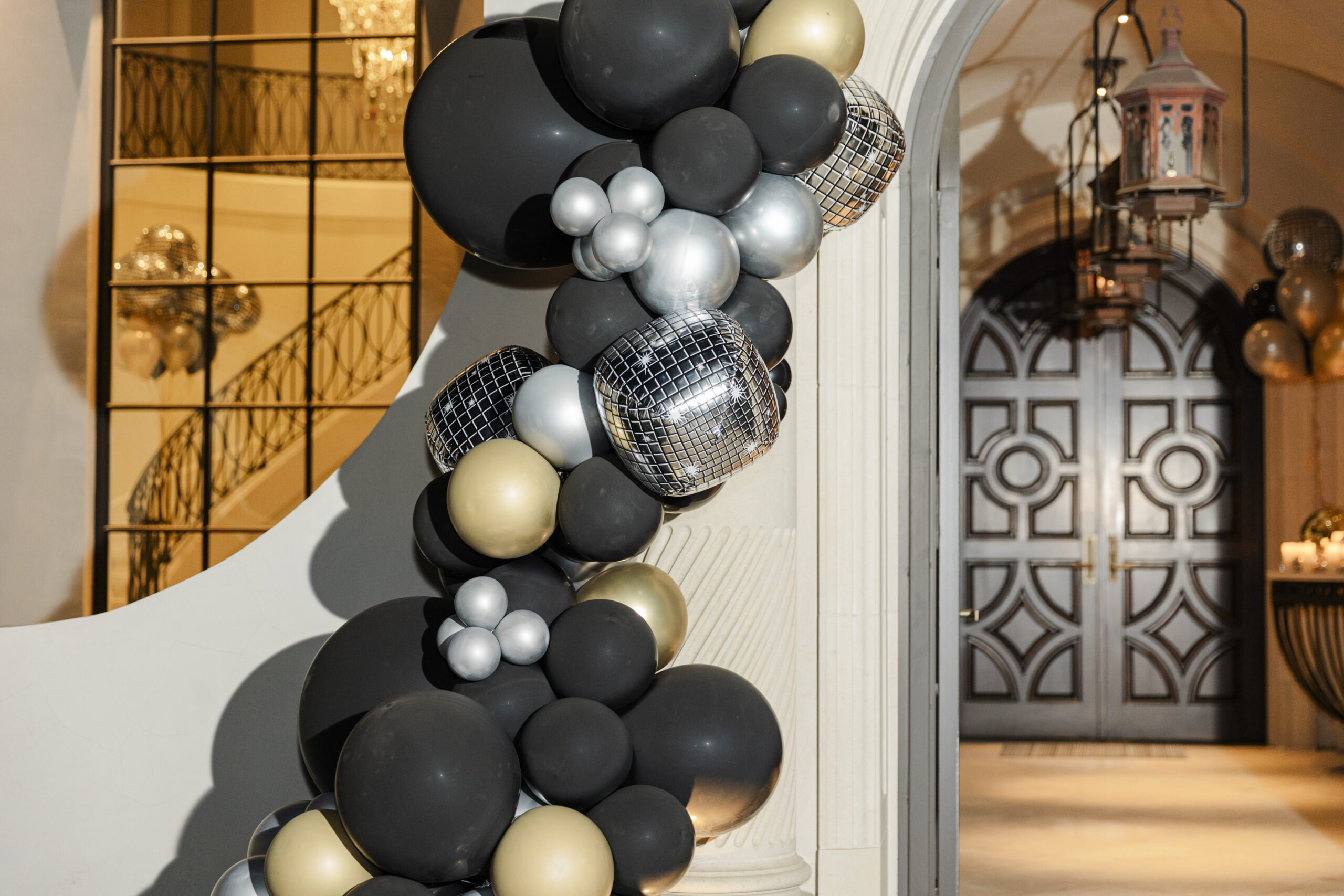 an elaboraqte balloon arch in front of an entryway to a home