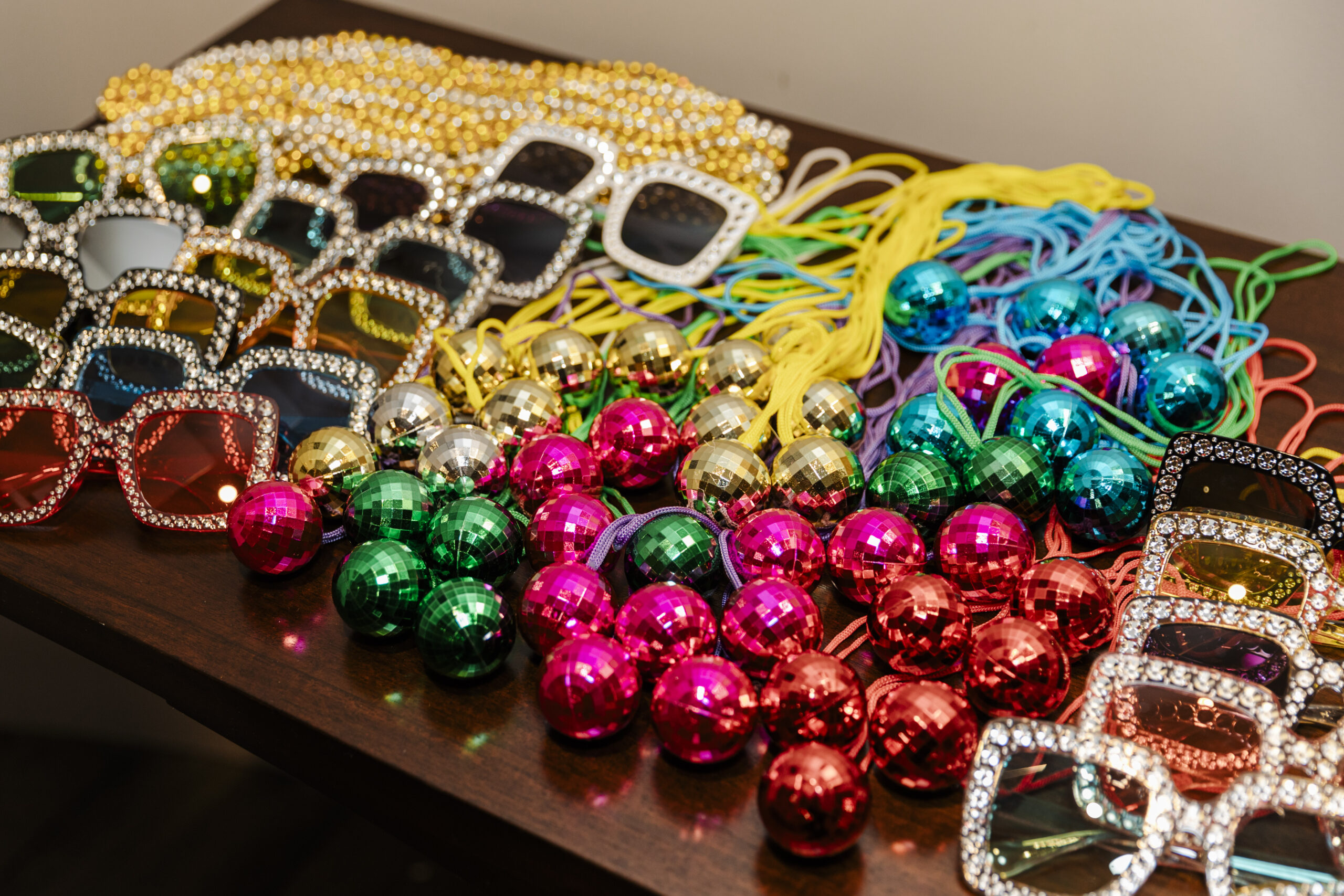 glasses, disco balls, and necklaces on top of a table for a birthday party