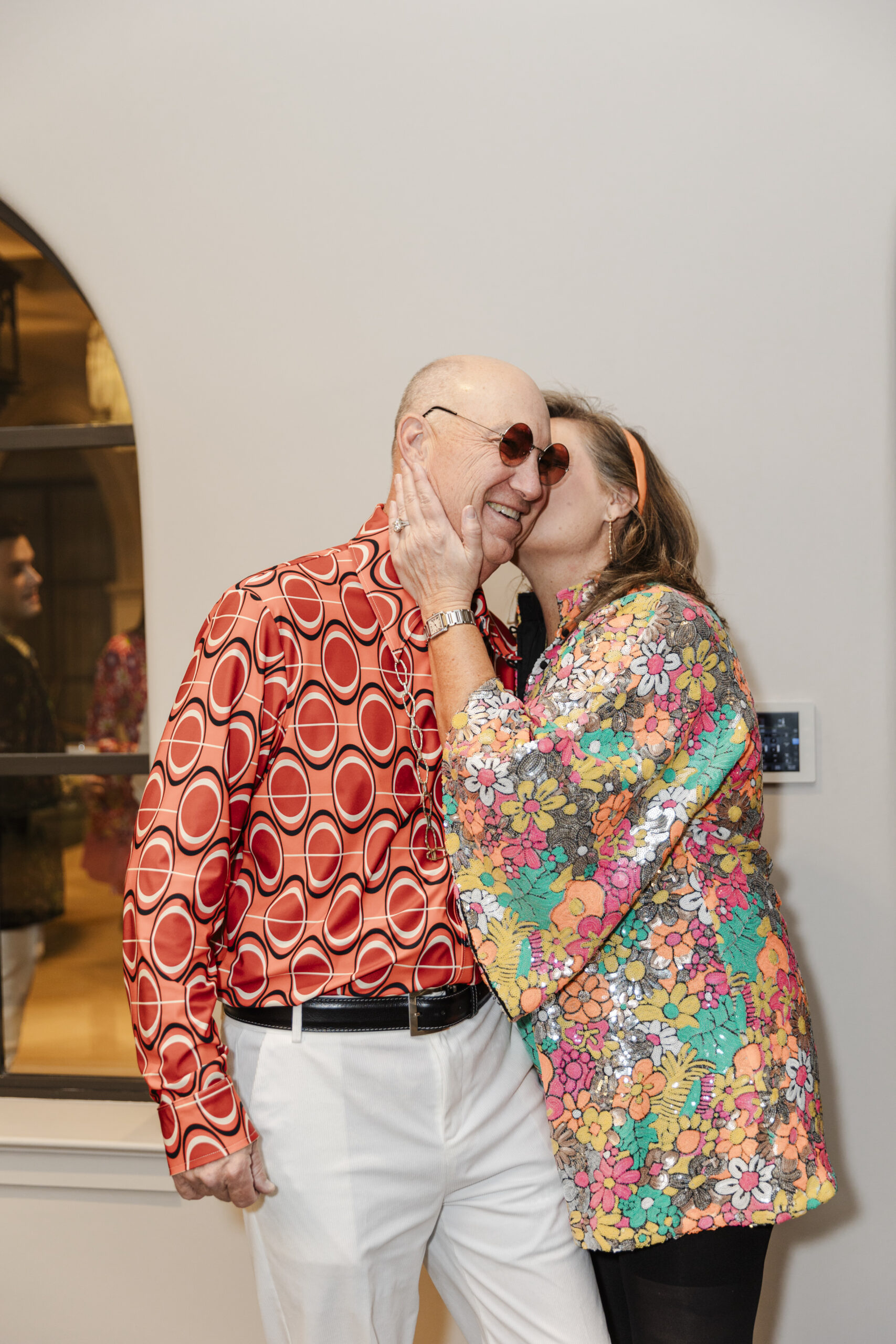 a woman kissing her husband on the cheek at his birthday party