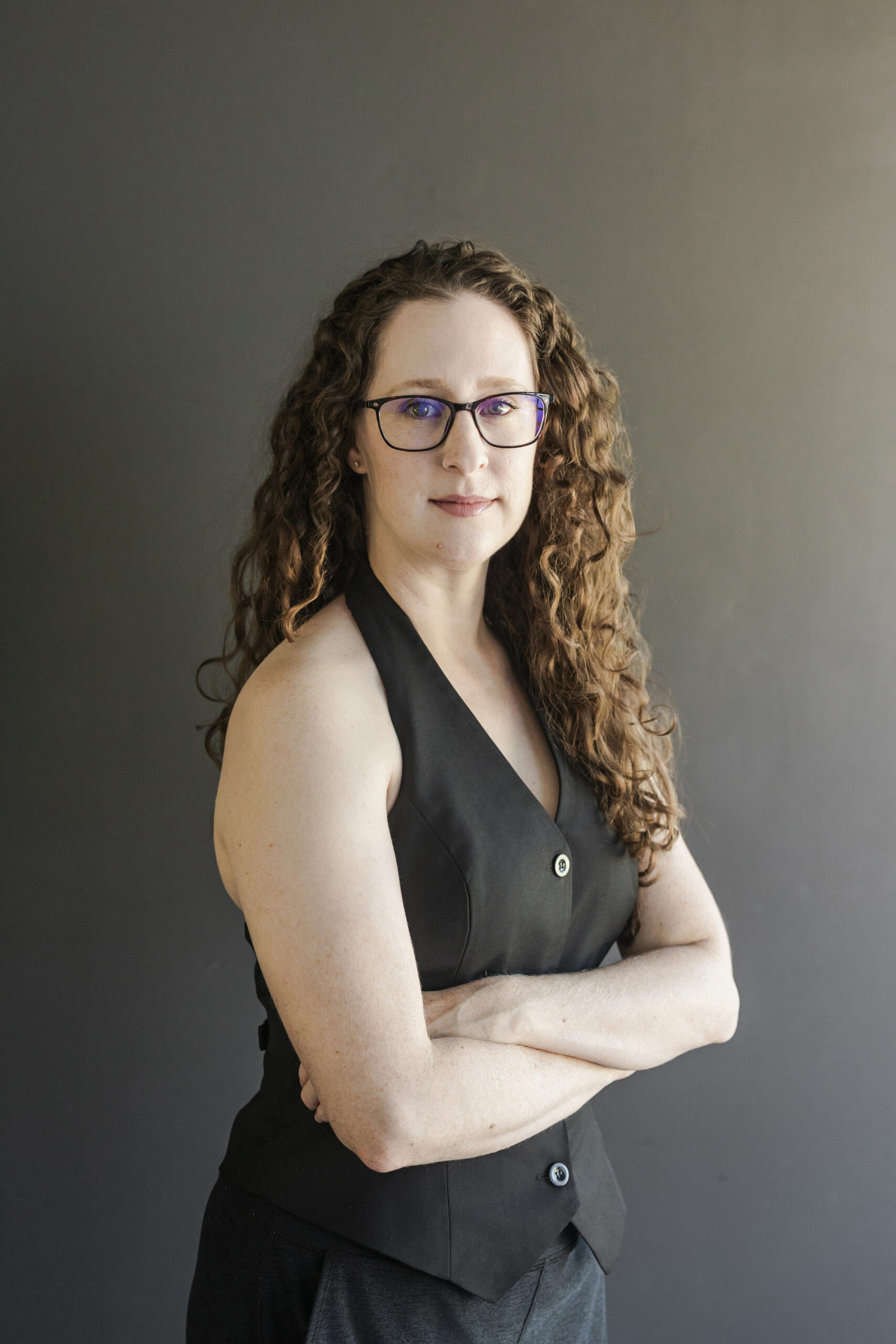 an author taking personal branding photos at sol and sage studios in richardson texas she is wearing glasses and has her arms crossed 