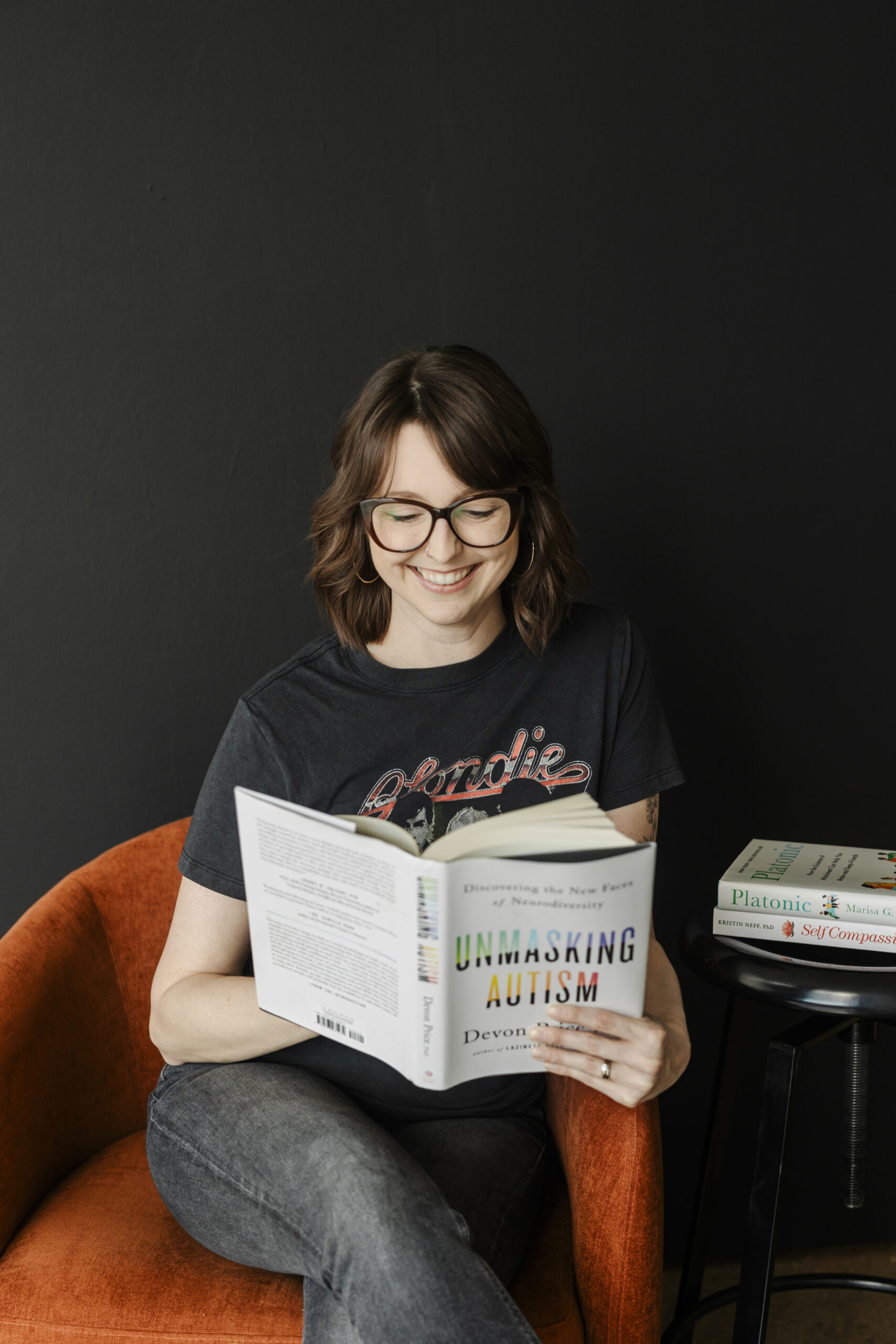 a therapist sitting in a red chair reading a book taking personal branding photos at the space on south side in dallas 