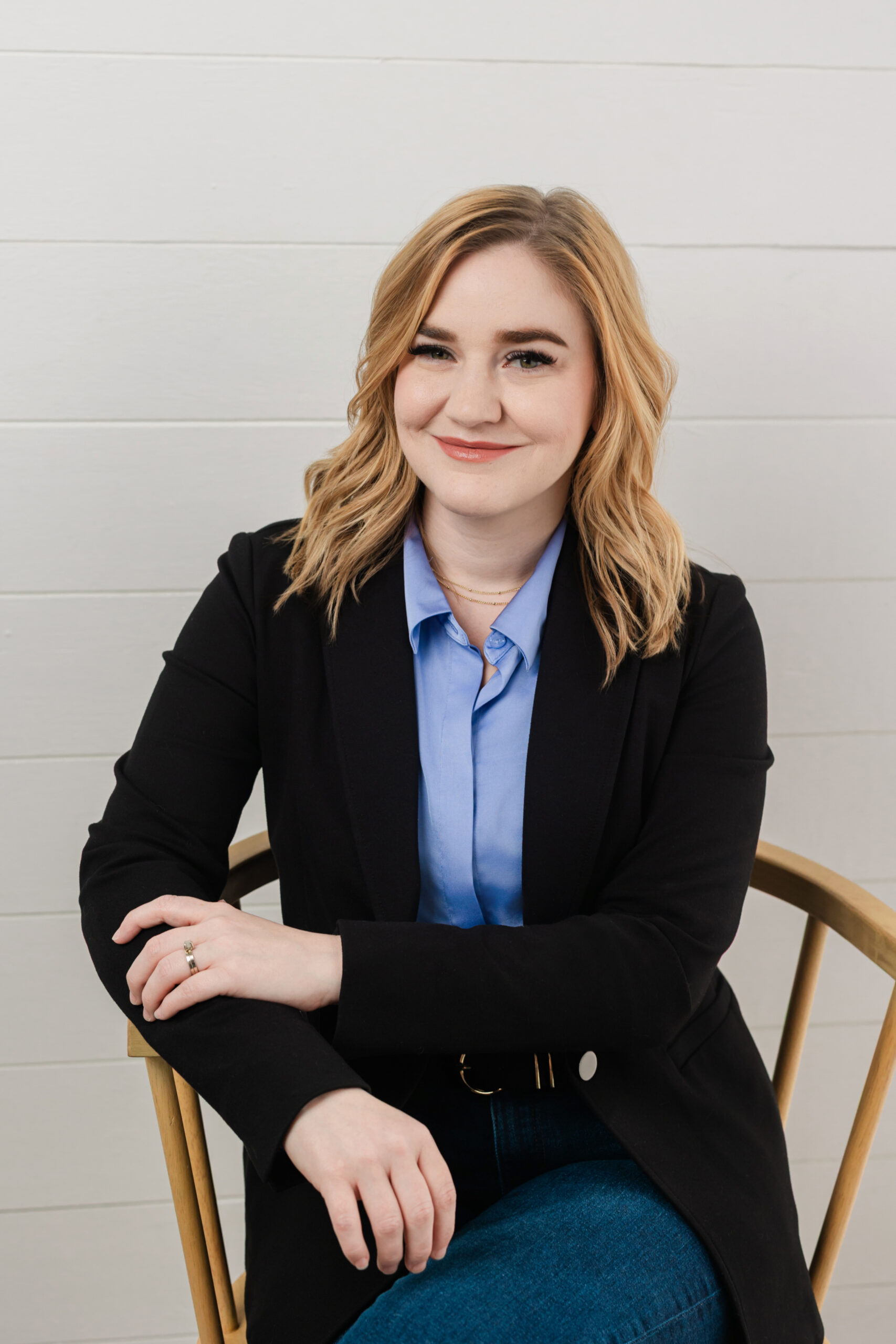a woman sitting in a chair taking a professional headshot in a studio in dallas