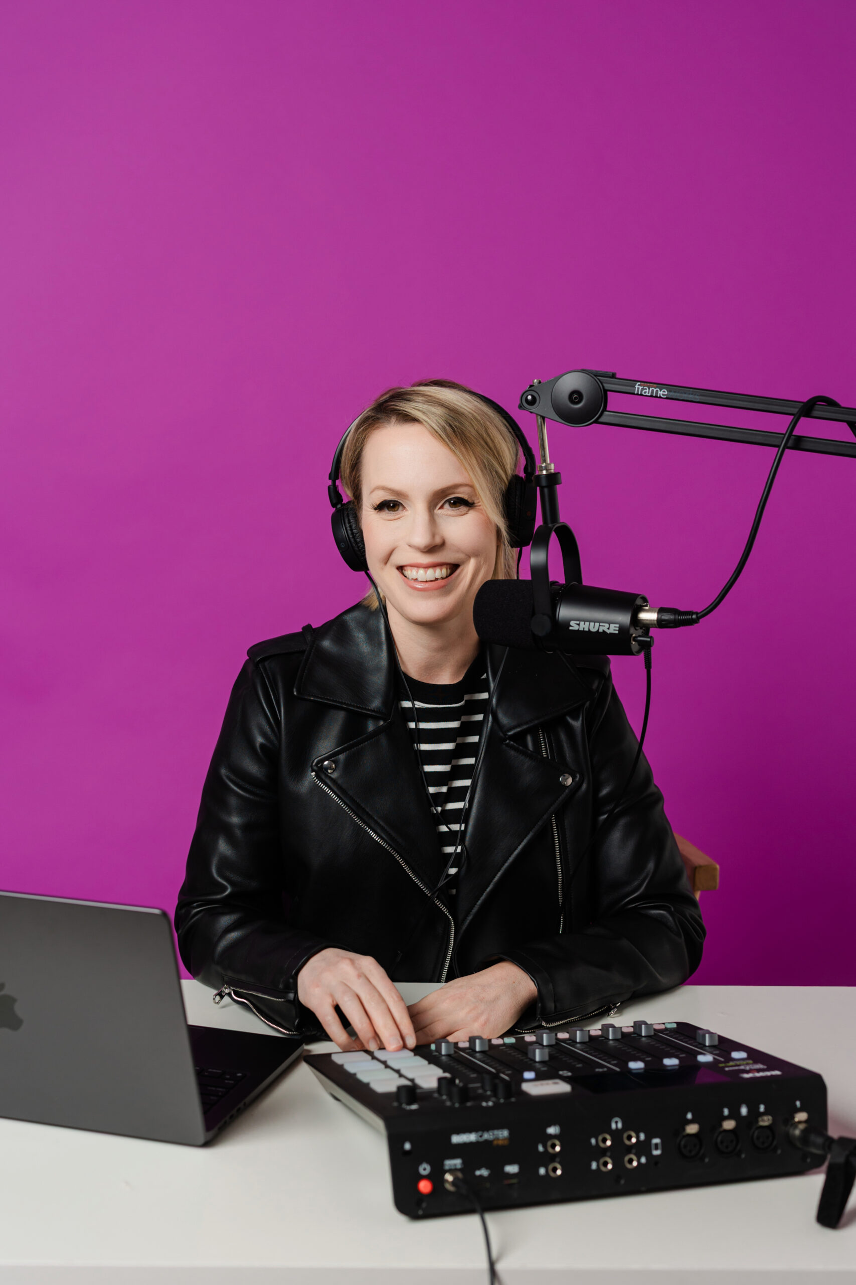 a woman with a studio set up and microphone having a professional headshot session with a purple backdrop