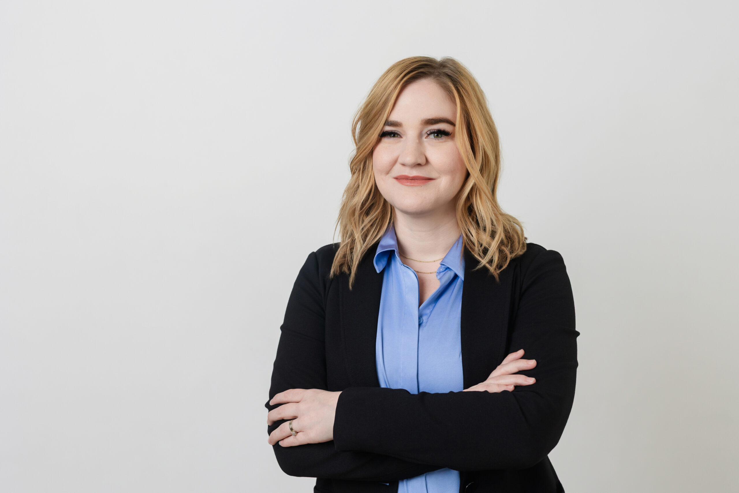a woman with her arms crossed in front of her taking professional headshot at a studio in dallas