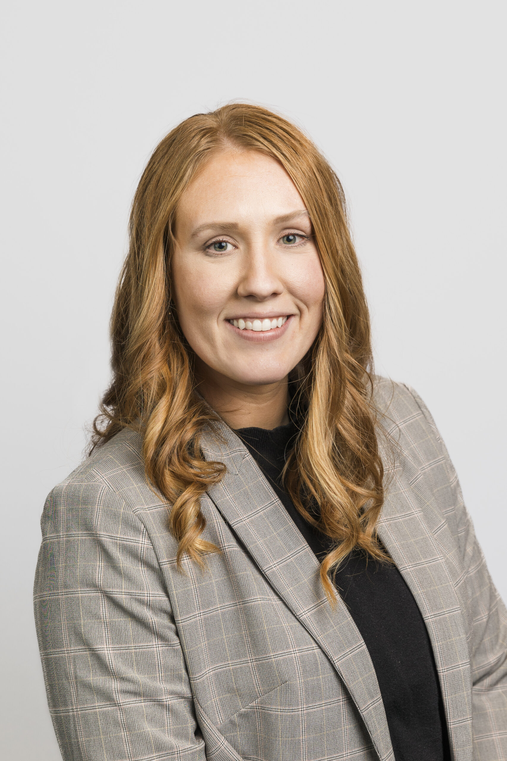 a woman in a black shirt and blazer taking a corporate headshot 