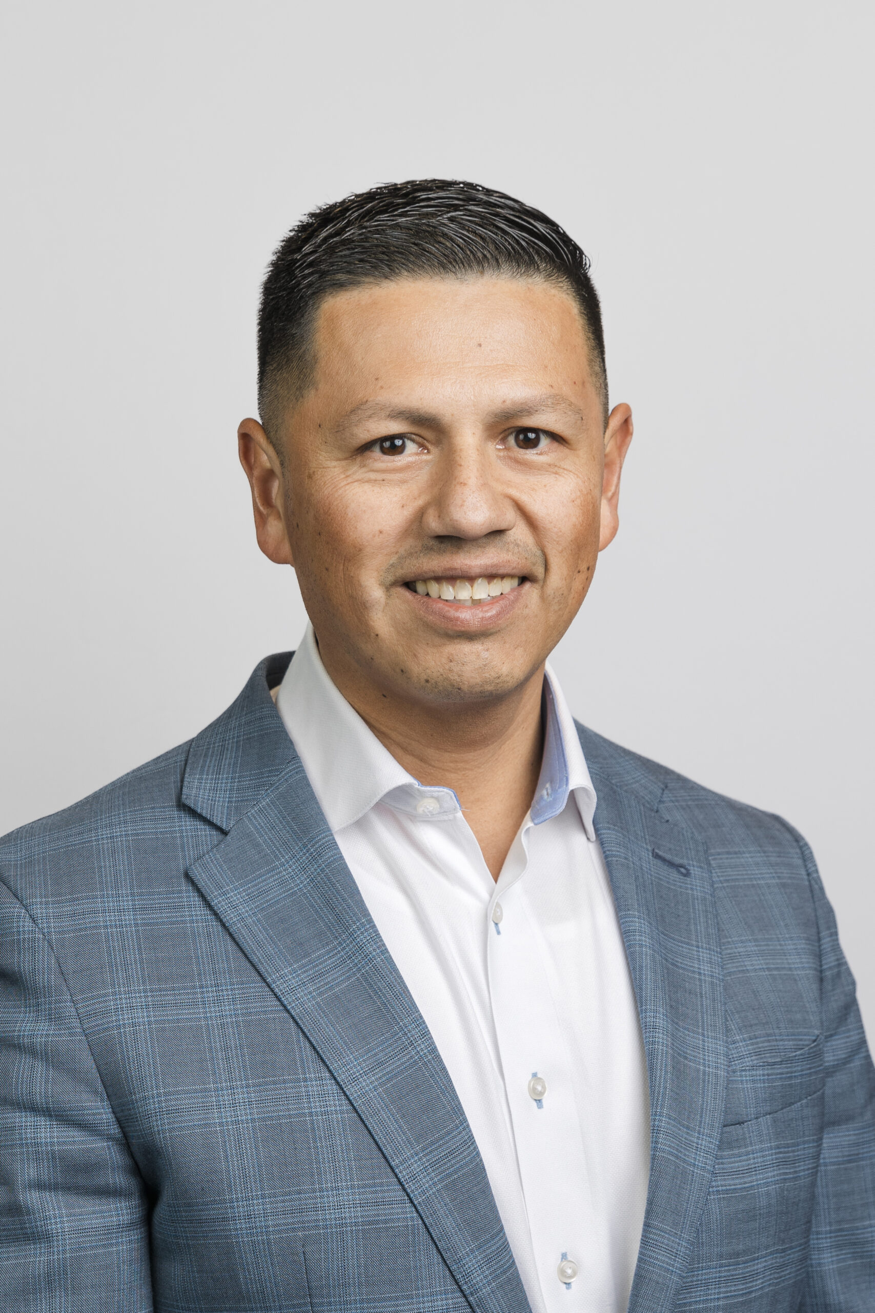 a man in a white button up and blazer taking a corporate headshot 